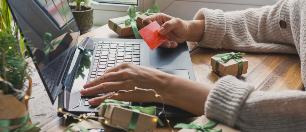 Womans' hands with gift around, holding a credit card and typing on laptop