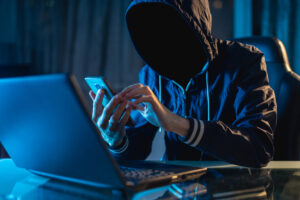 Anonymous hacker programmer uses a laptop to hack the system in the dark.