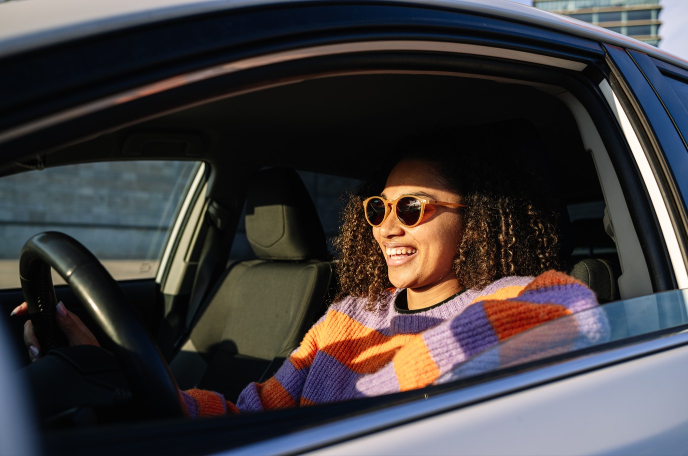 Young woman smiling with sunglasses driving in the car.