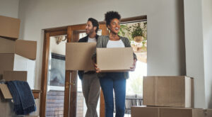 Man and African American women moving into home with boxes in their hands