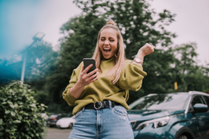 Young women cheering while looking at phone