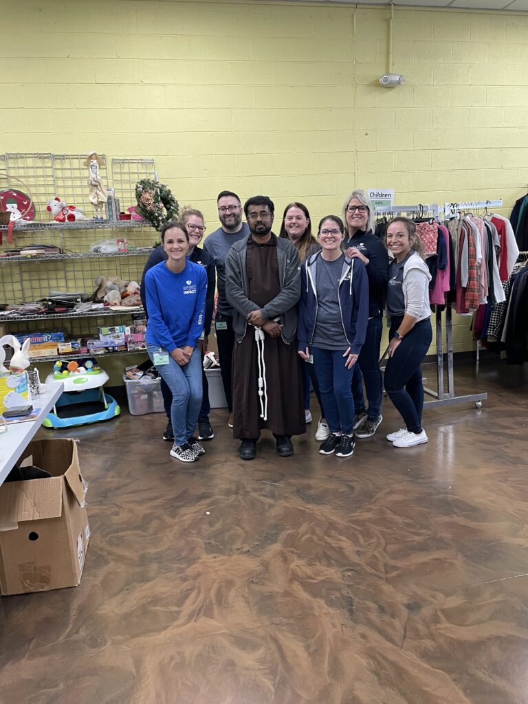 CFCU employees smiling with Capuchin priest.